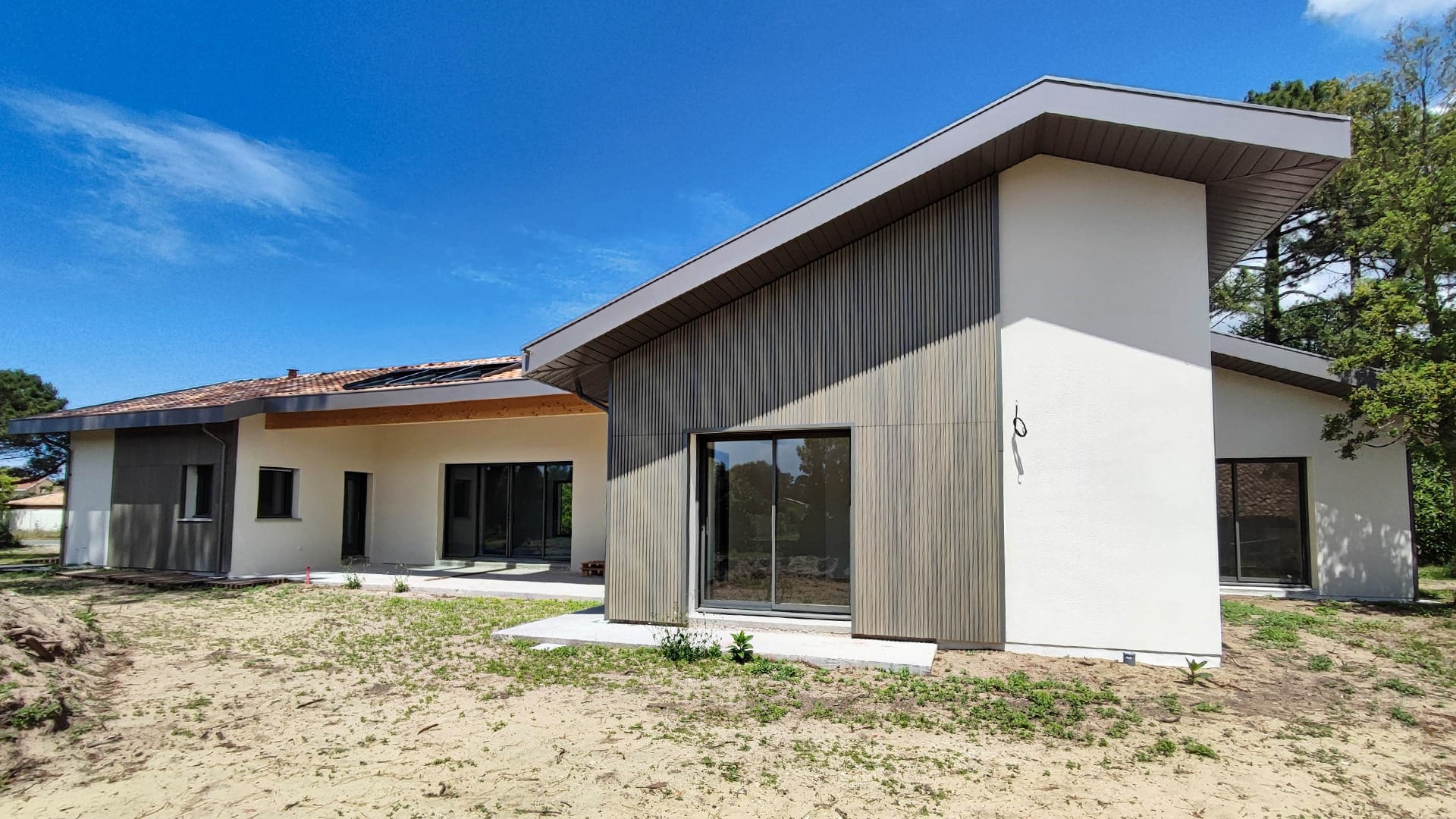 Construction maison Vieux-Boucau : Villa de 174 m² avec 3 suites - Maison Landes Habitat Maison moderne avec un design en bois et des grandes fenêtres, située dans un environnement dégagé.