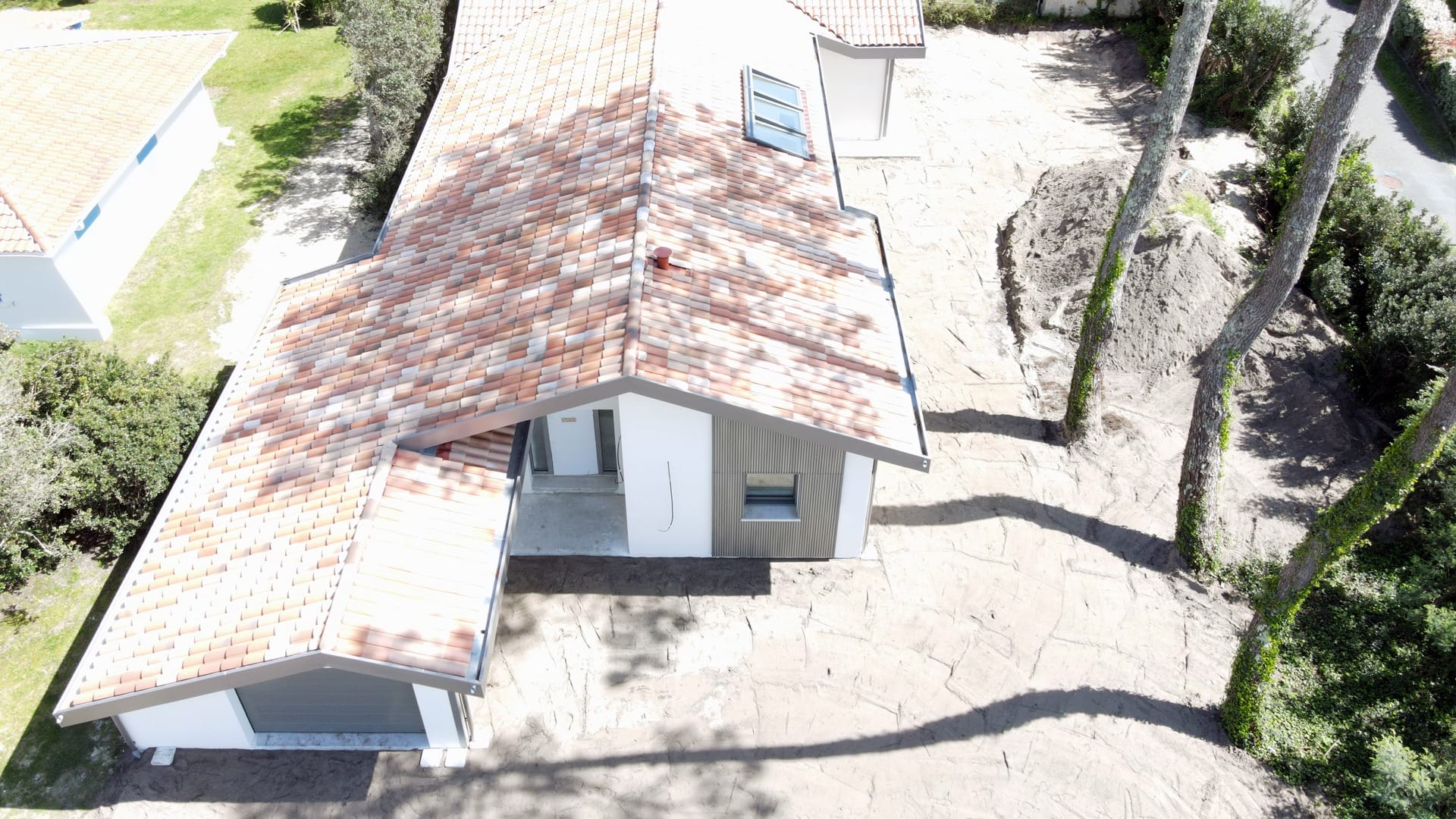Construction maison Vieux-Boucau : Villa de 174 m² avec 3 suites - Maison Landes Habitat Vue aérienne d'une maison moderne avec un toit en tuiles et une allée en pierre.