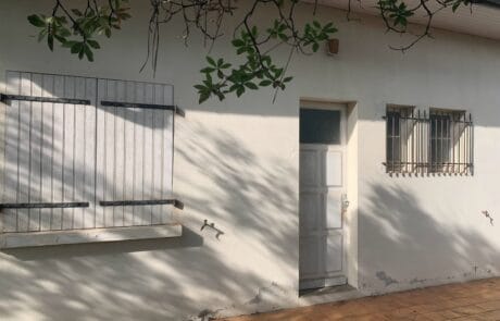 Façade d'une maison avec une porte blanche et des fenêtres à volets en bois.